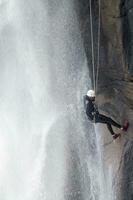 un persona en un cuerda alpinismo arriba un cascada foto