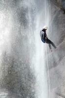 a person on a rope climbing up a waterfall photo