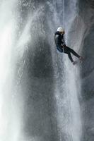 a person on a rope climbing up a waterfall photo