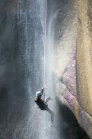 a person on a rope climbing up a waterfall photo