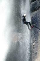 un persona en un cuerda alpinismo arriba un cascada foto