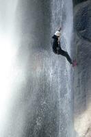 a person on a rope climbing up a waterfall photo