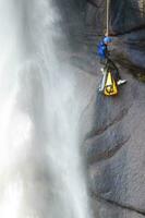 un persona en un cuerda alpinismo arriba un cascada foto