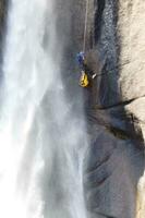 un persona en un cuerda alpinismo arriba un cascada foto