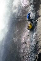 un persona en un cuerda alpinismo arriba un cascada foto