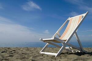 un playa silla en el arena con un azul cielo foto