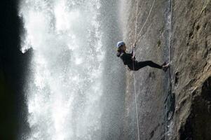 un persona en un cuerda alpinismo arriba un cascada foto