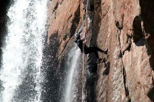 a person on a rope climbing up a waterfall photo