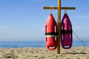 two life preservers are on a pole on the beach photo