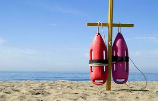 two life preservers are on a pole on the beach photo