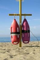 two life preservers are on a pole on the beach photo