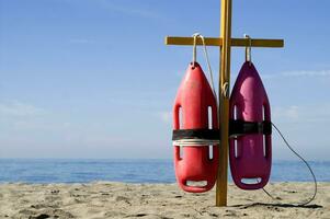 two life preservers are on a pole on the beach photo