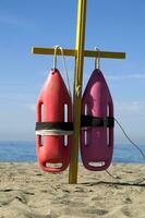 two life preservers are on a pole on the beach photo