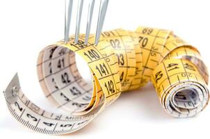 a fork and knife surrounded by measuring tape photo