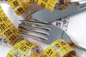 a fork and knife surrounded by measuring tape photo