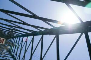 the sun shines through the metal structure of an oil rig photo