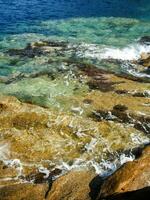 un rocoso apuntalar con olas estrellarse en contra el rocas foto