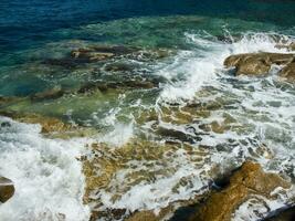 un rocoso apuntalar con olas estrellarse en contra el rocas foto