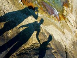shadow of two people on rocks near water photo