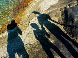 sombra de dos personas en rocas cerca agua foto