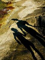 shadow of two people on rocks near water photo