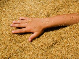 a child's hand is in a pile of sand photo