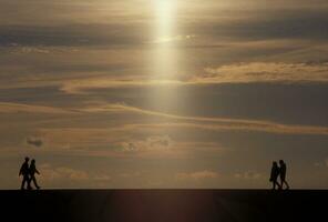 Tres personas caminando en un playa con el Dom brillante mediante el nubes foto