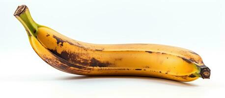 A banana that is spoiled and black can be seen on a white background. It has a brown spot and is photo