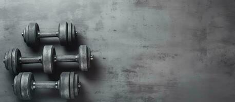 Background image of old iron dumbbells placed on a grey concrete floor in a gym. The photo is taken