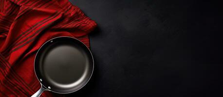 Top view of an empty frying pan and napkin on a black background, with copy space available photo