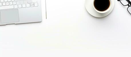 A top view of a white office desk with a notebook, keyboard, pencil holder, and a cup of coffee. photo