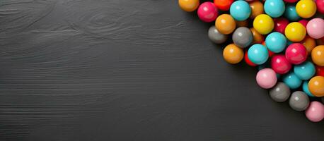 A horizontal banner with copy space featuring colorful candy balls on a gray and black paper photo