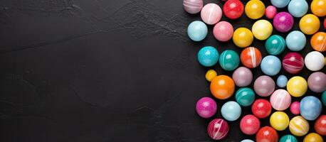 Colorful candy balls arranged on a gray and black paper background in a horizontal banner format photo