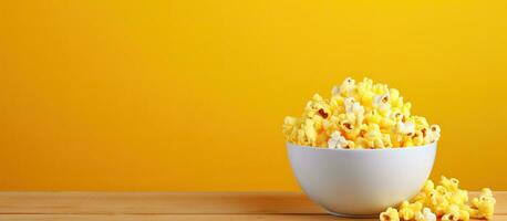 The bowl of colorful popcorn sits on a yellow desk with a view from above, providing ample copy photo