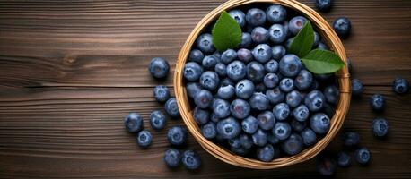Ripe blueberries are displayed in a wicker bowl on a rustic wooden table. is taken from above, photo