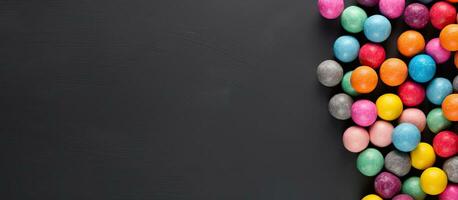 Colorful candy balls arranged on a gray and black paper background in a horizontal banner format photo