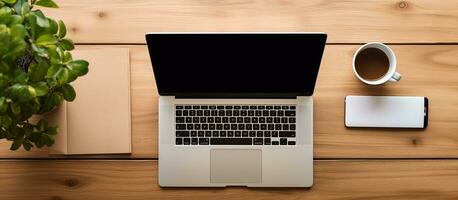 Wooden office desk table with laptop and smartphone displaying a black blank mockup screen, photo