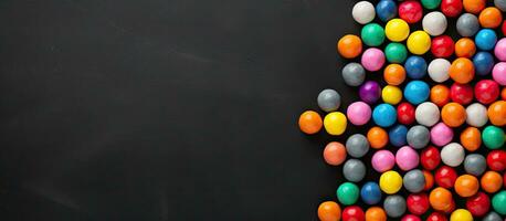 Colorful candy balls arranged on a gray and black paper background in a horizontal banner format photo