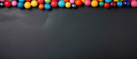 A horizontal banner with copy space featuring colorful candy balls on a gray and black paper photo