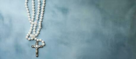 A white canvas with a painted background displaying a blue-beaded rosary, viewed from the top, photo