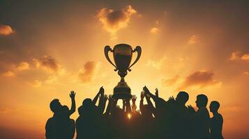 Victorious team triumphs under sunset with trophy and numerous silhouetted hands photo