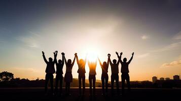 Group of business team members raising hands in the sunset sky background to depict teamwork photo