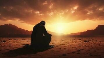 Muslim praying at dusk in the desert photo