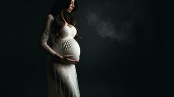 Pregnant woman in white dress close up of belly Studio pregnancy shoot black background photo