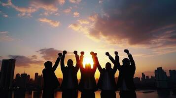 Group of business team members raising hands in the sunset sky background to depict teamwork photo