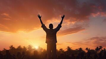 Human silhouette raising hands in prayer to God on blurred sunset background with cross and crown of thorns photo