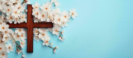 Religious themed flat lay featuring a wooden cross and spring flowers on a blue background photo