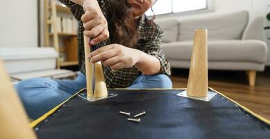 Asian Woman self repairs furniture renovation using equipment to diy repairing furniture sitting on the floor at home photo