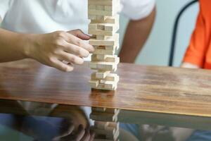 Asian father and son playing wood blocks game Carefree kid playing wood blocks game building constructor from blocks with father at home photo