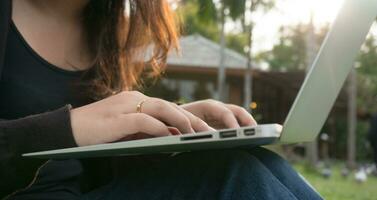 mujer sentado en parque en el verde césped con computadora portátil, estudiante estudiando al aire libre. Copiar espacio para texto foto